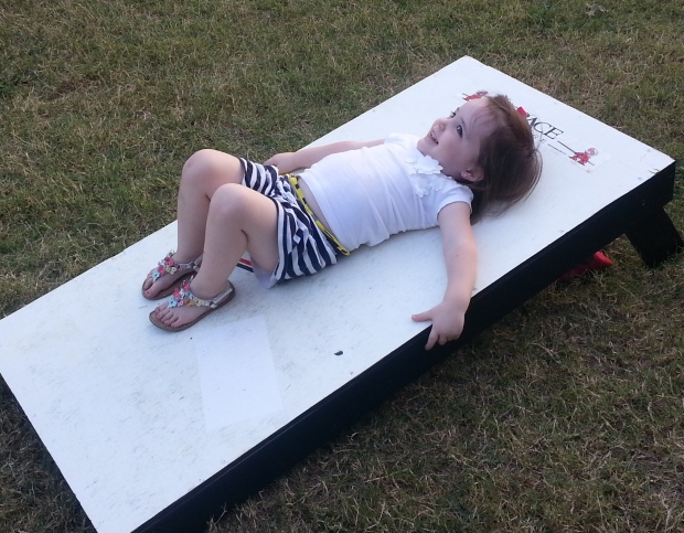 [August] She doesn't quite understand the game of corn hole. Never a dull moment with this child...